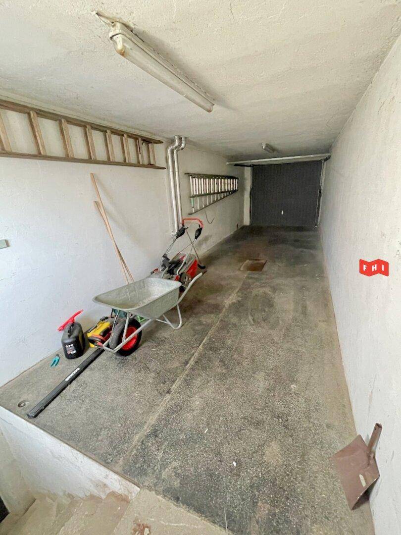 Garage mit Betonboden, Werkzeugen und Zugang zum Außenbereich.