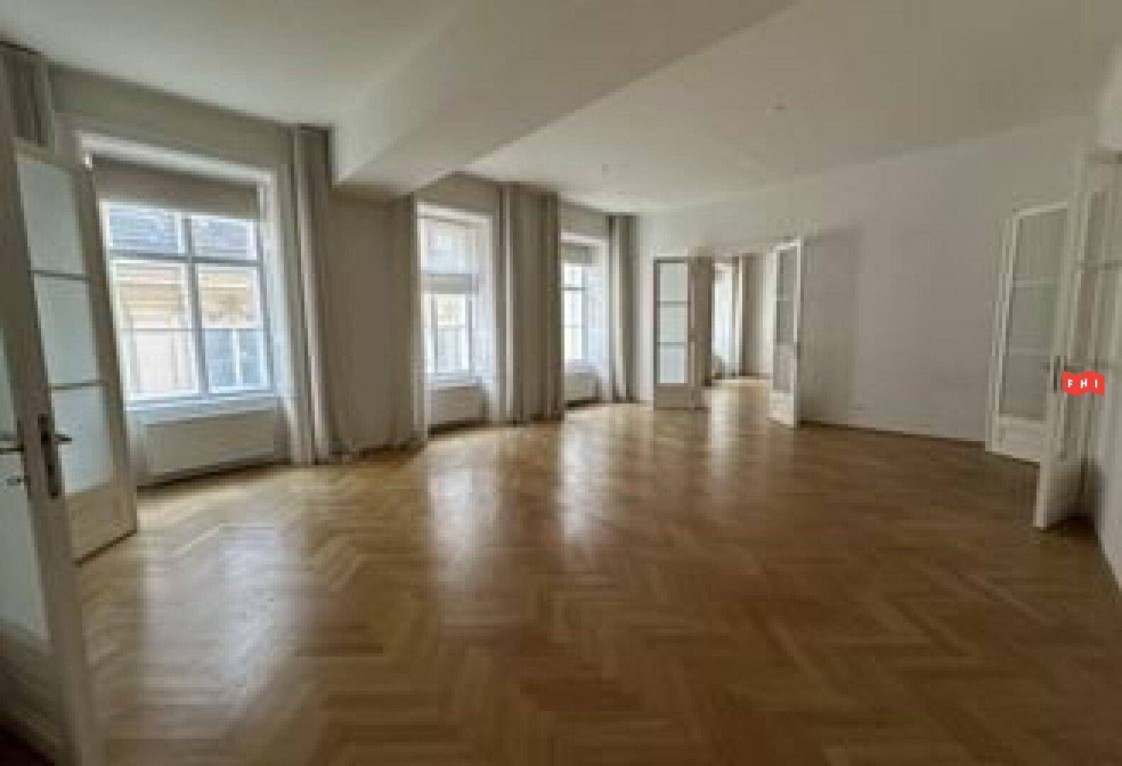 Klassischer Wohnraum mit Fischgrätparkett, hohen Fenstern und Flügeltüren.