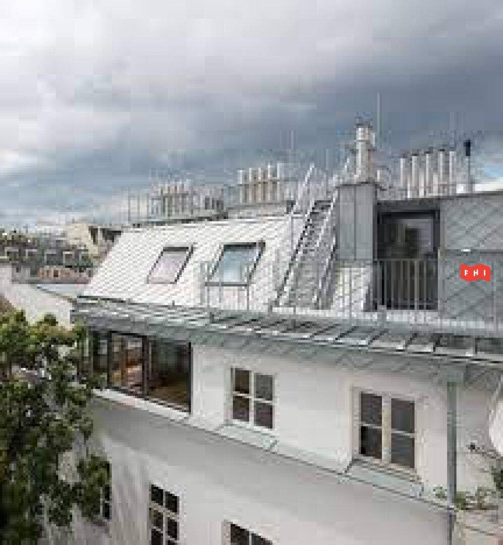 Dachgeschossausbau eines Gebäudes mit modernen Dachfenstern und einer Dachterrasse unter bewölktem Himmel.