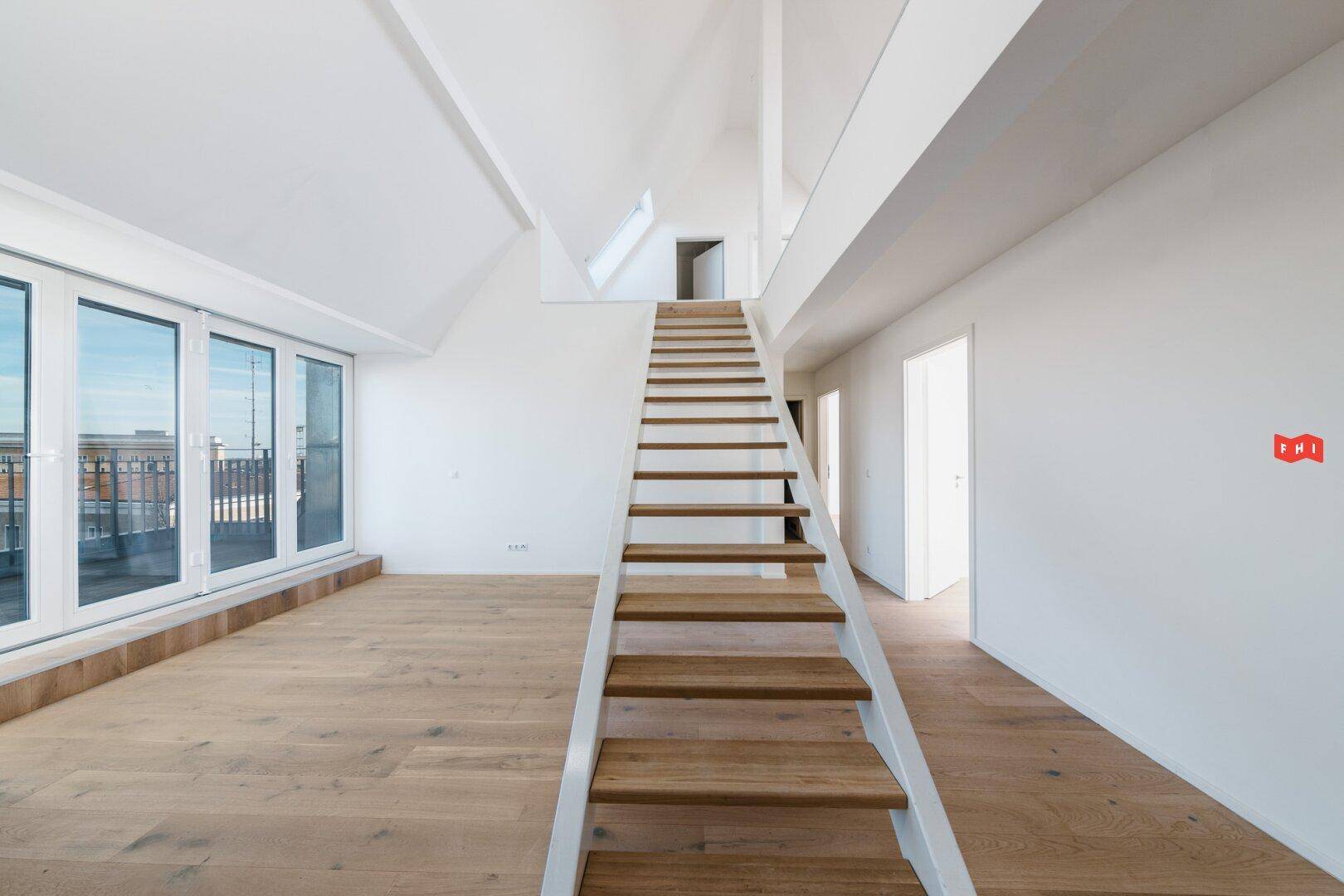 Heller, offener Raum mit moderner Holztreppe, großen Schiebetüren und Dachschrägen.