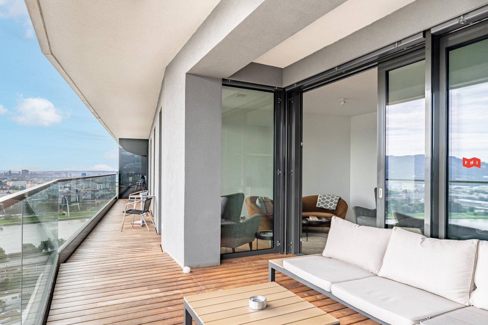 Großer Balkon mit Sitzgelegenheiten und Zugang zum Innenbereich, bietet weite Stadtblicke.
