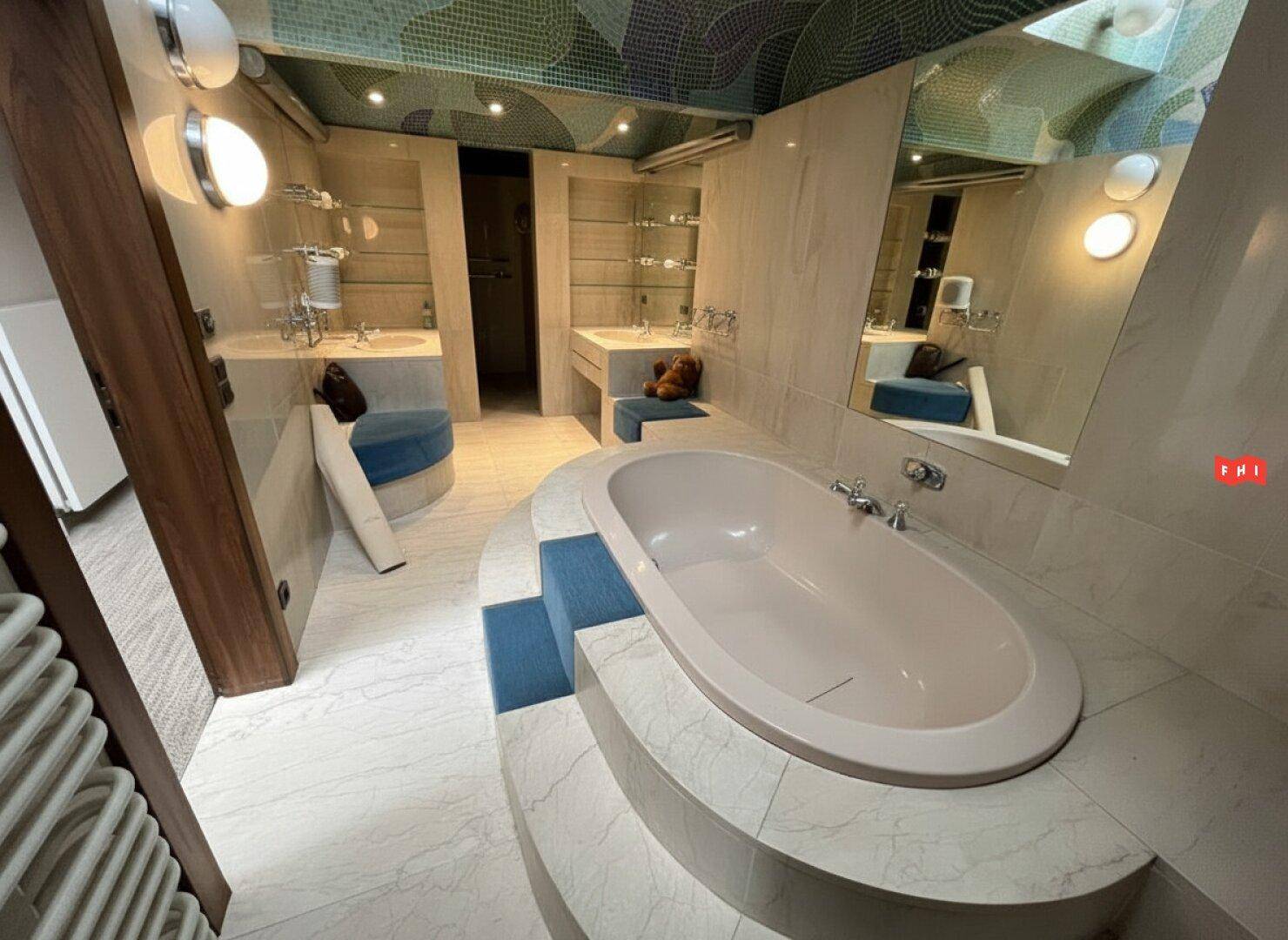 Luxuriöses Badezimmer mit ovaler Badewanne auf einer erhöhten Plattform und doppelten Waschbecken.