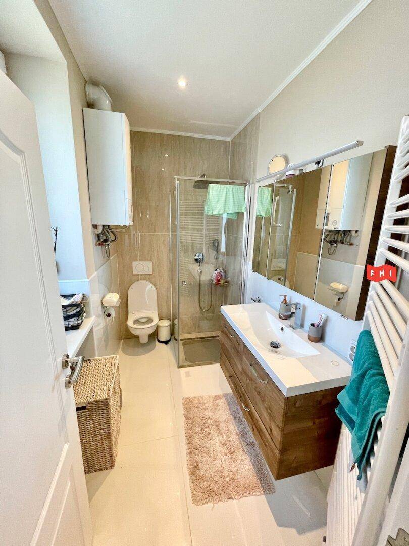 Modernes Badezimmer mit begehbarer Dusche, Waschtisch und beheiztem Handtuchhalter.