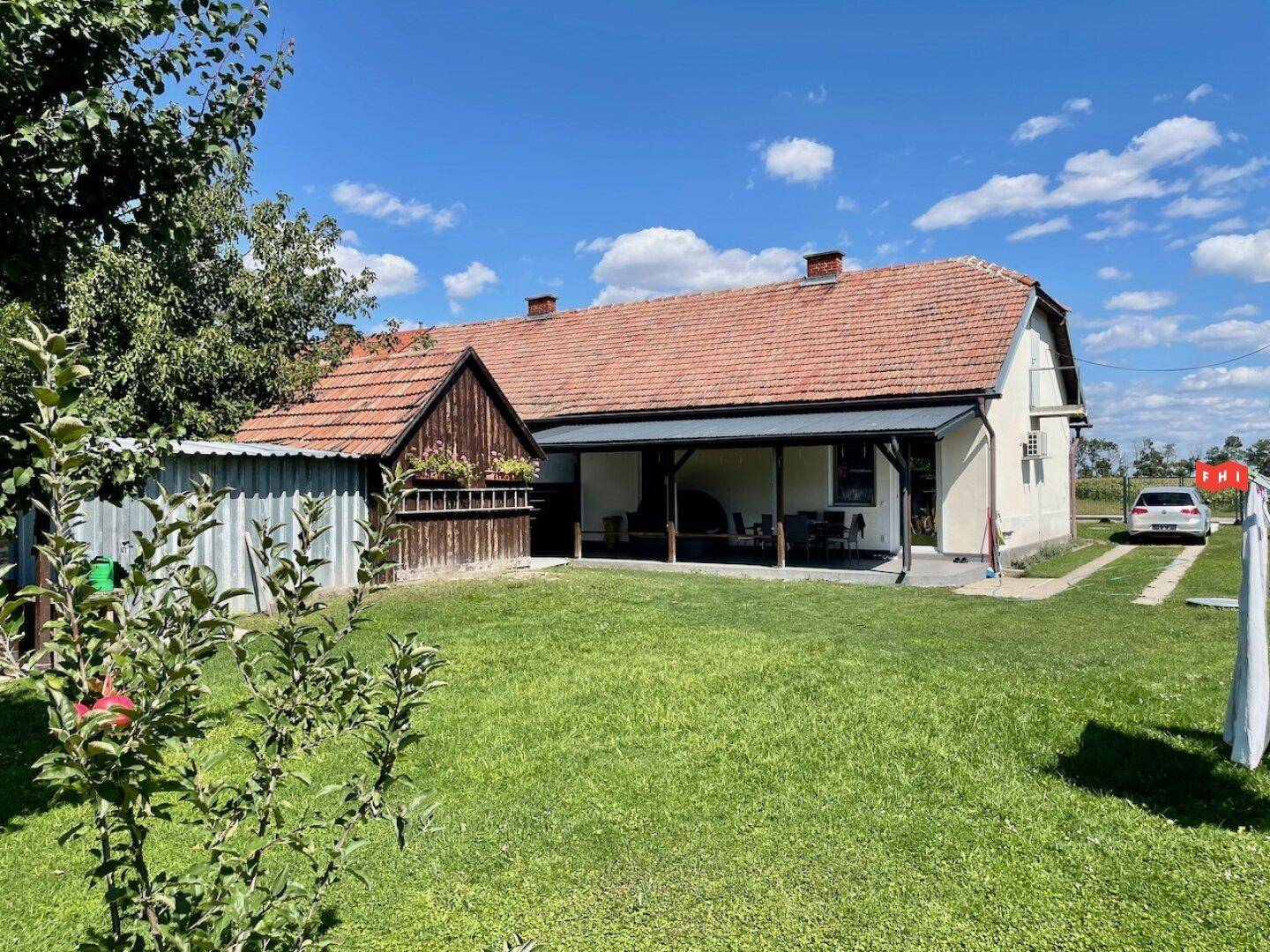 Großer grüner Garten mit Wäscheleine und Blick auf das traditionelle Wohnhaus mit überdachter Terrasse.