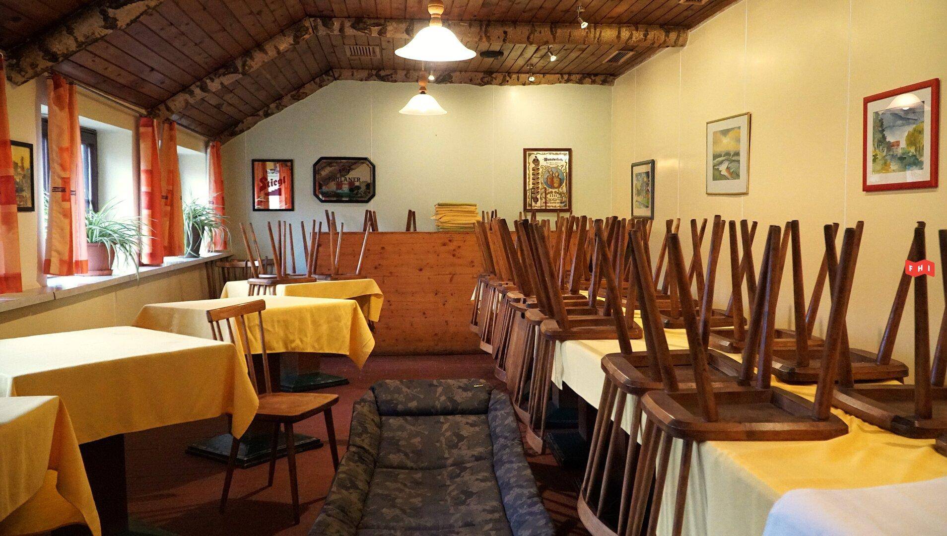 Gemütlicher Speisesaal mit Holzbalkendecke und Tischen, die für die Reinigung oder Schließung vorbereitet sind.