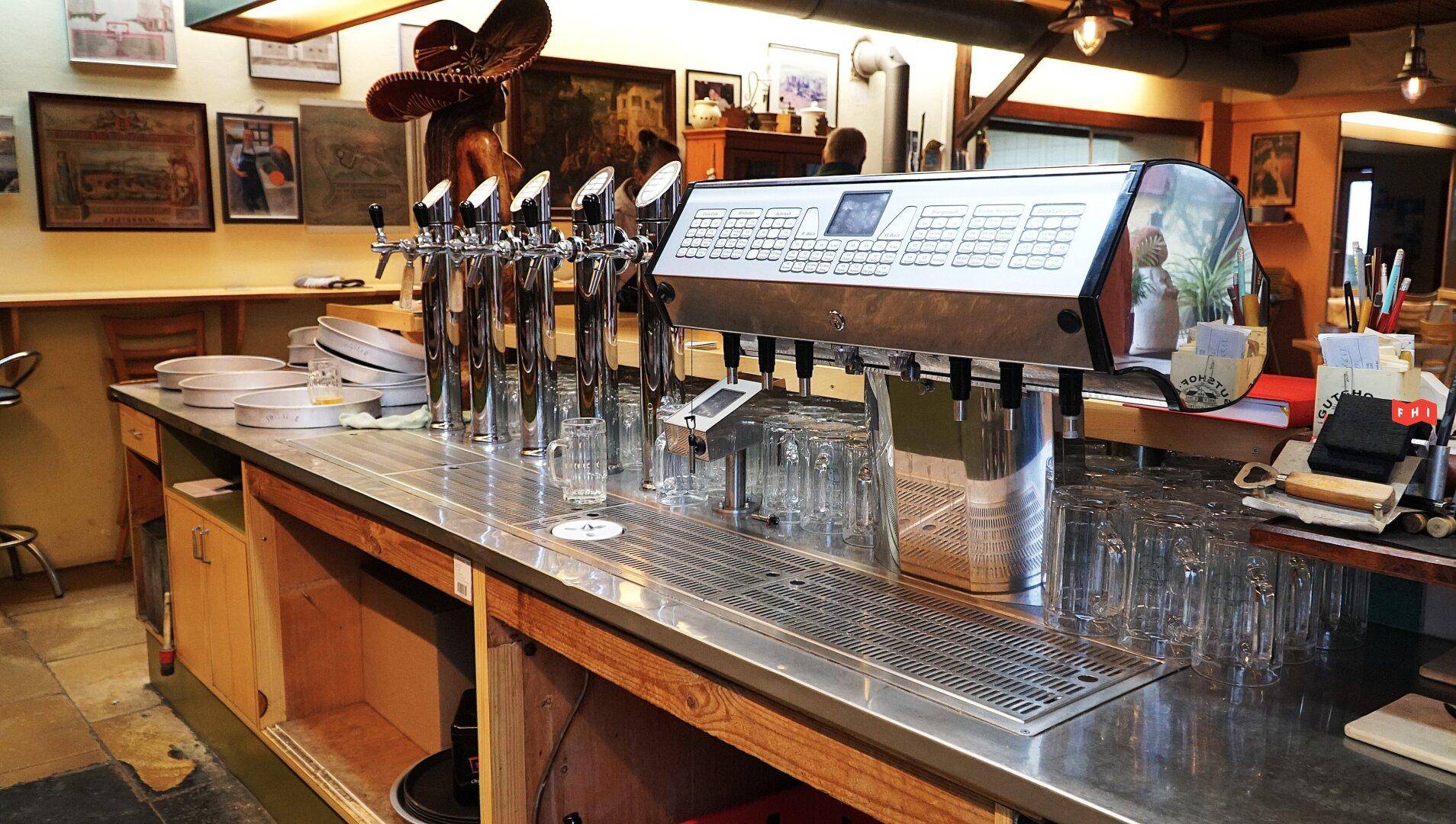 Detailansicht der Bar mit glänzenden Zapfhähnen und einem Kassensystem, bereit für den Service.