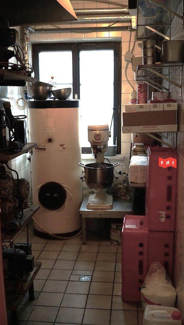 Funktionsraum mit großem Warmwasserspeicher, einer Küchenmaschine und Regalen, ideal für die Vorbereitung.