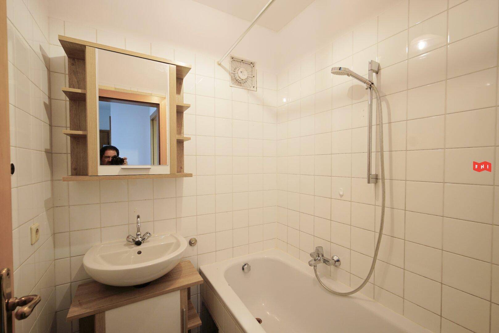 Funktionales Badezimmer mit Badewanne, Waschbecken und weiß gefliesten Wänden.