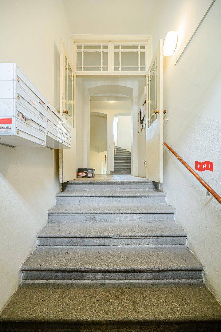 Eingangsbereich eines Mehrfamilienhauses mit Treppe, Briefkästen und Zugang zu den Wohnungen.