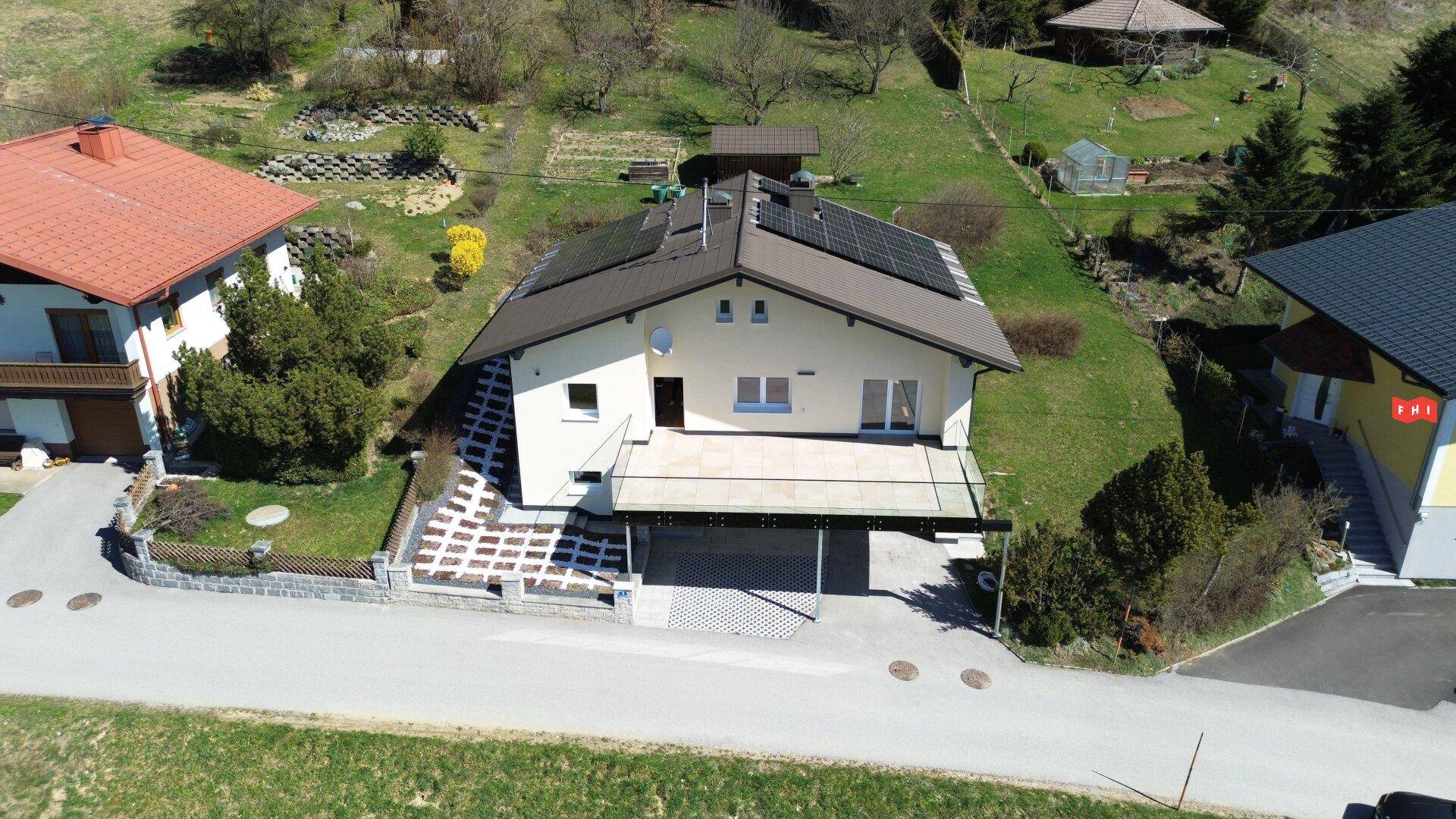 Gesamtansicht des modernen Hauses mit Solaranlage, Terrasse und Carport in ländlicher Lage.