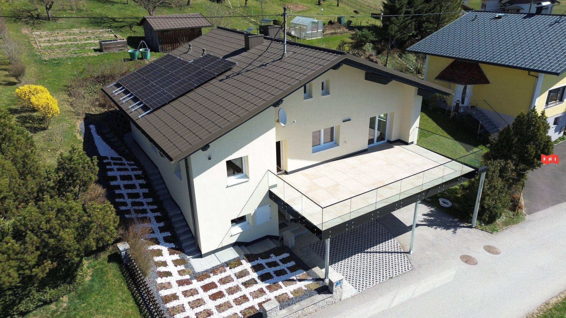 Ansicht des Hauses von oben mit moderner Terrasse und überdachtem Carport im ländlichen Umfeld.