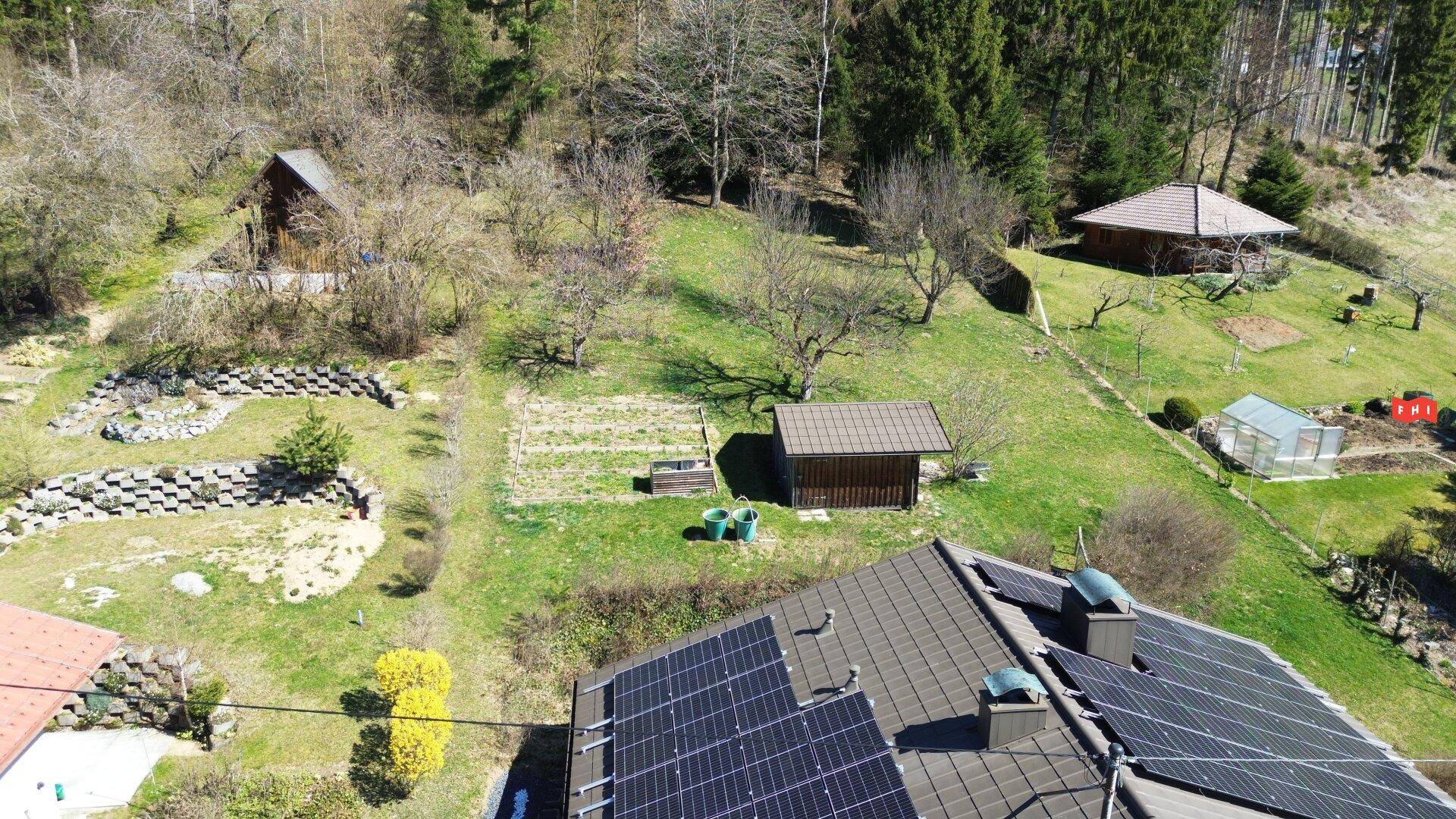 Luftaufnahme des weitläufigen Gartens mit Gartenhaus, Obstbäumen und Gemüsegarten.