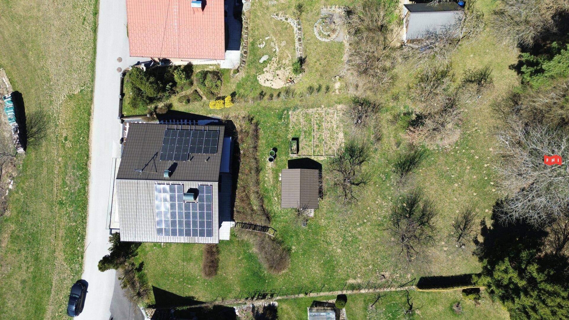 Vogelperspektive des Anwesens mit Haus, großem Garten und angrenzenden Grünflächen.