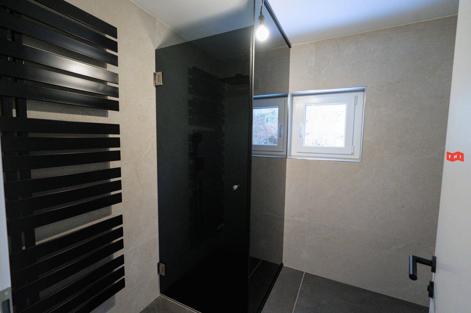 Elegantes Badezimmer mit begehbarer Dusche, beheiztem Handtuchhalter und Fenster.