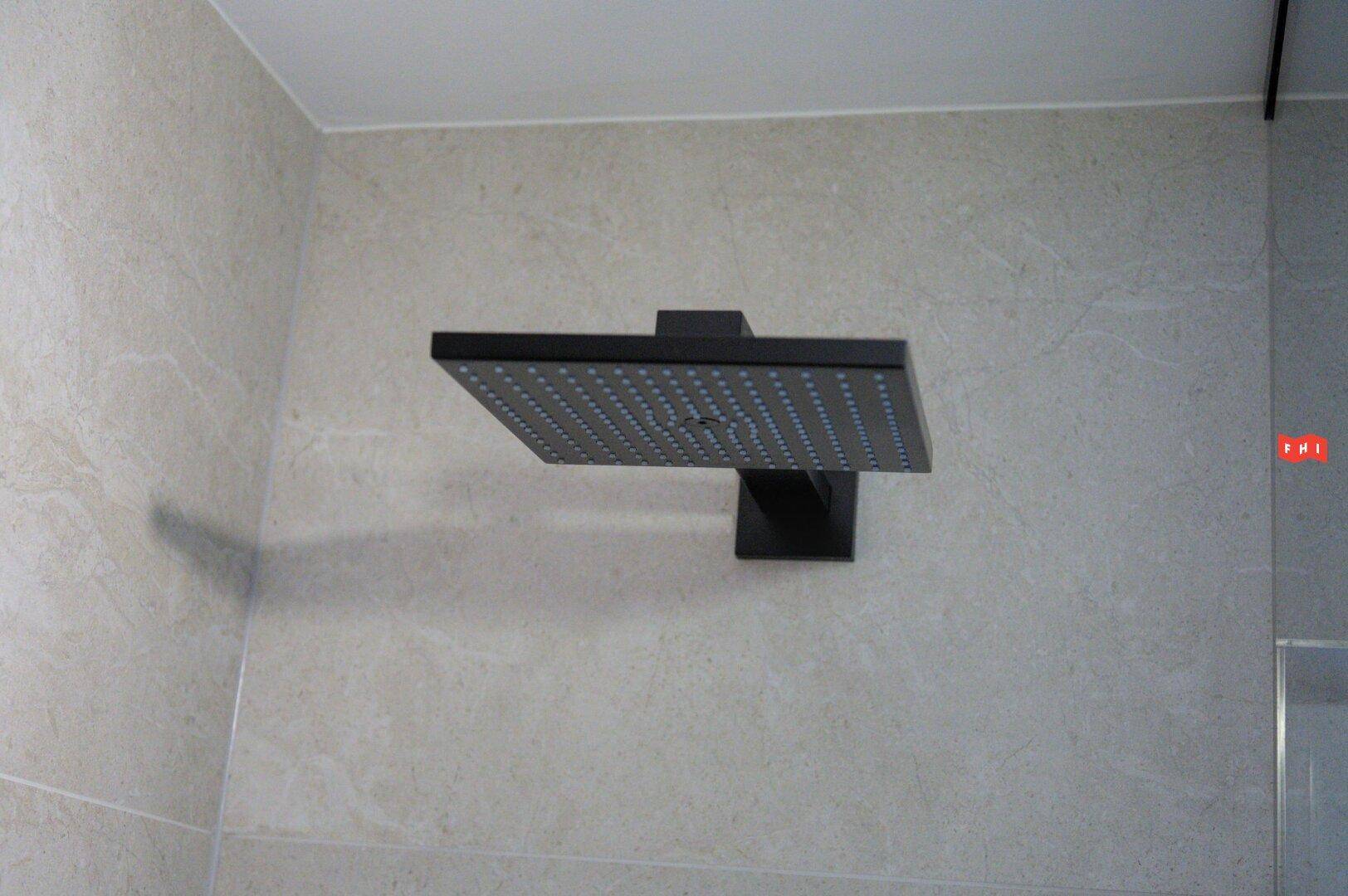 Moderne Regendusche mit schwarzem Duschkopf in einem stilvollen Badezimmer.