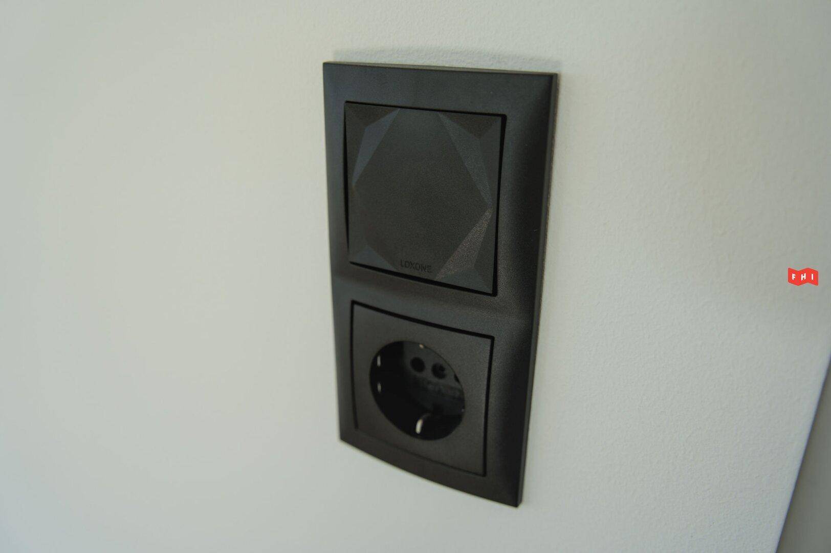 Schwarzer Lichtschalter und Steckdose an einer weißen Wand, modernes Design.