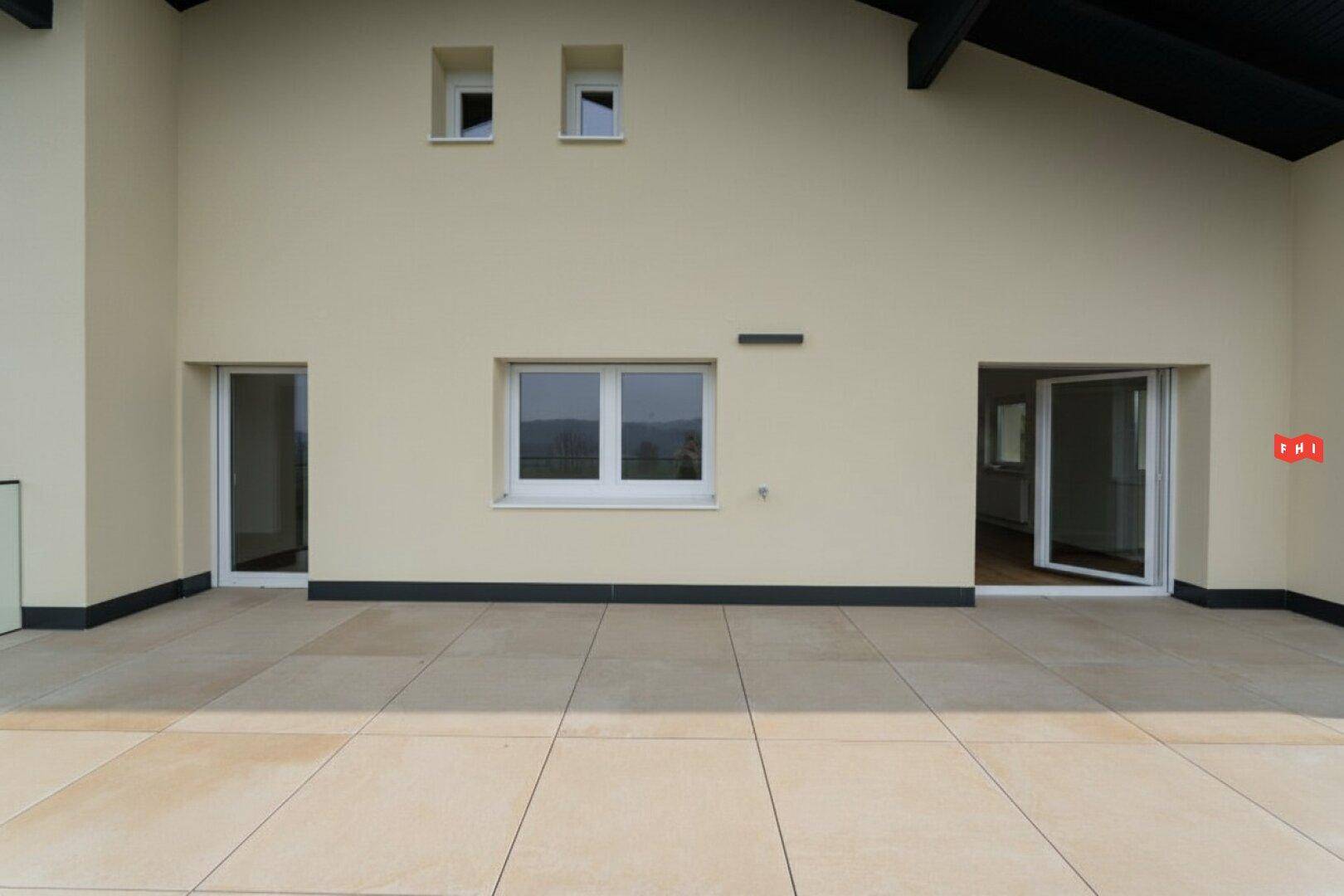 Fassade des Hauses vom Terrassenbereich aus gesehen, mit mehreren Fenstern und Türen.