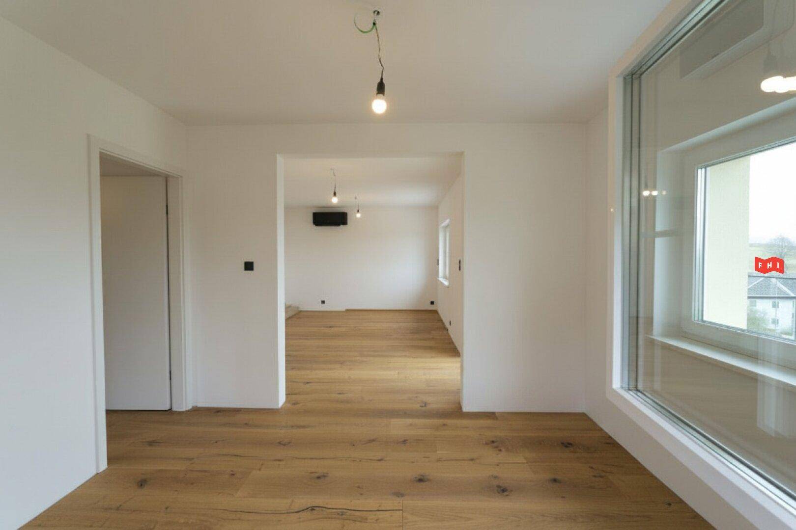 Geräumiger, heller Innenraum mit hochwertigem Holzboden und offener Gestaltung.