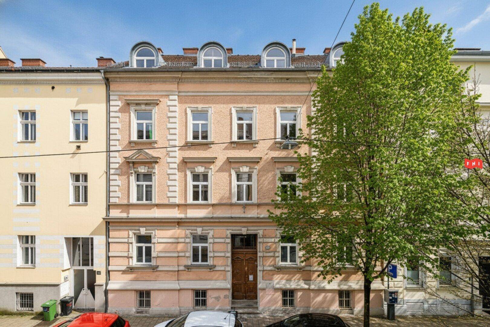 Historisches Mehrfamilienhaus mit klassischer Fassade und Bogenfenstern im Dachgeschoss.