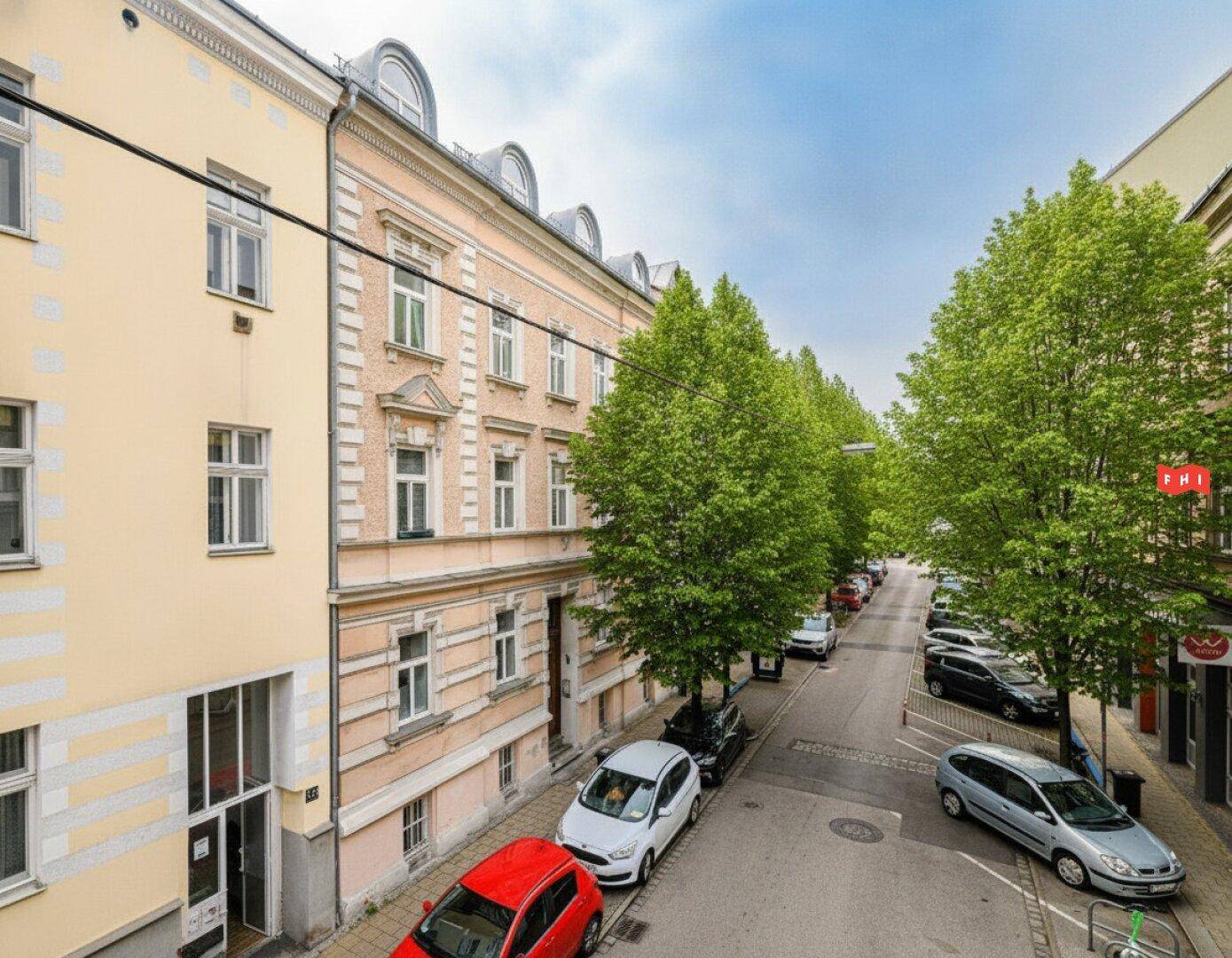 Blick auf die Straße mit parkenden Autos und dem historischen Gebäude.