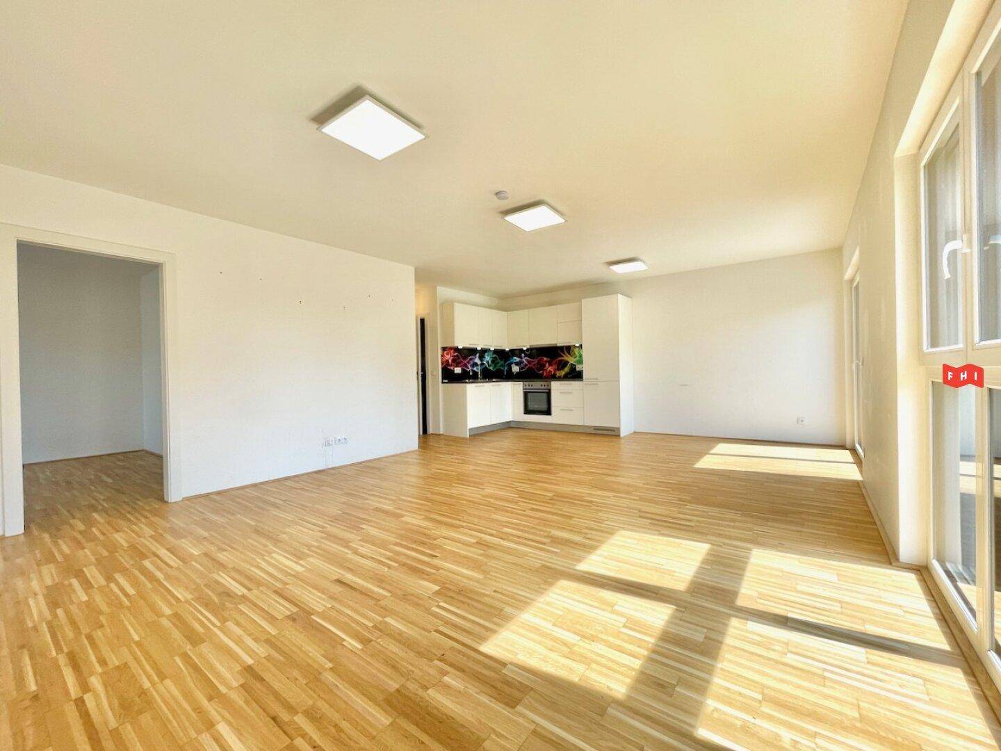 Lichtdurchfluteter Wohnbereich mit Parkettboden und moderner Küchenzeile, ideal für offenes Wohnen.