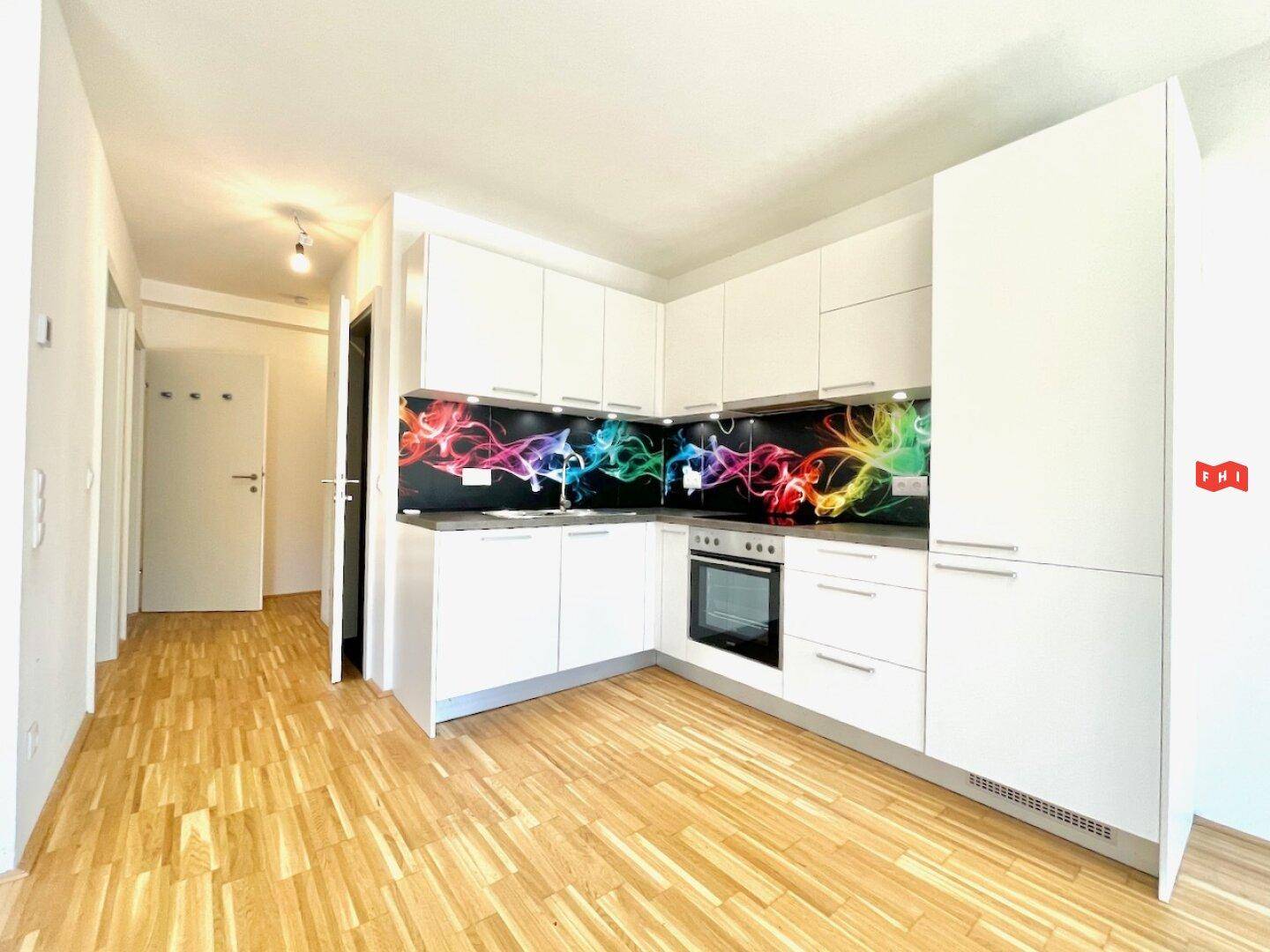 Moderne Einbauküche mit weißen Schränken, bunten Spritzschutz und integriertem Backofen.