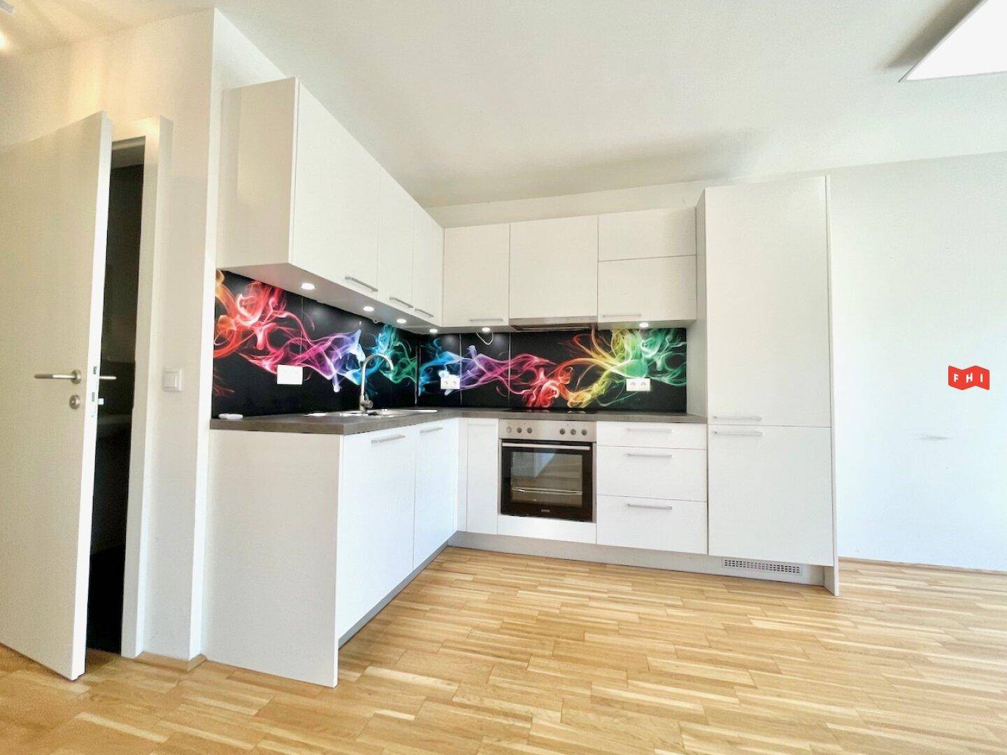 Stilvolle weiße Küche mit modernen Geräten und einem farbenfrohen Spritzschutz als Akzent.