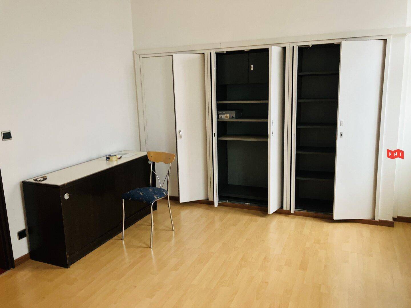 Funktionaler Raum mit Einbauschränken, hellem Holzfußboden und einfacher Möblierung.