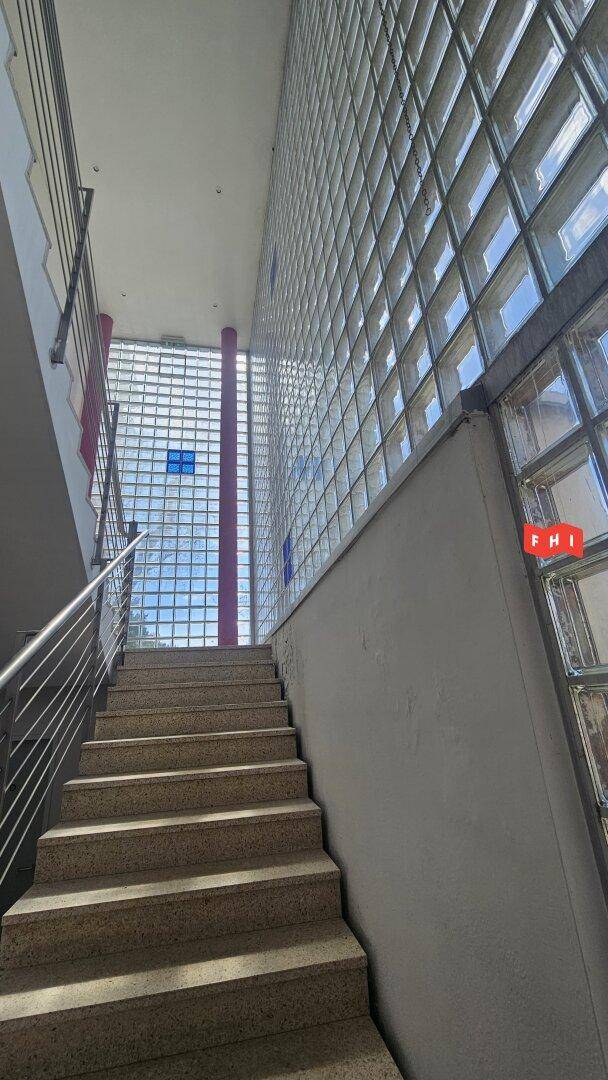 Treppenhaus mit Steinstufen und einer beeindruckenden Glasbausteinwand, die viel natürliches Licht hereinlässt.