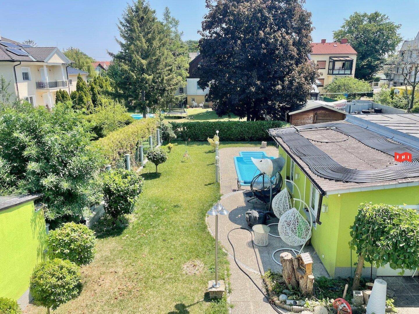 Weitläufiger Garten mit Pool, Rasenflächen und Bäumen, von oben betrachtet.