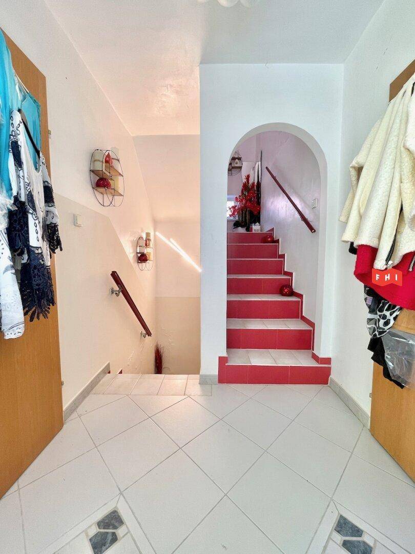 Flur mit roter Treppe, weißem Geländer und Zugang zu weiteren Räumen.