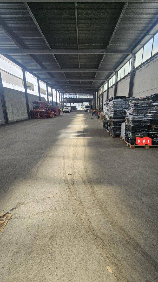 Überdachter Außenbereich mit Betonboden und Metallkonstruktion, möglicherweise eine Laderampe oder ein Carport.