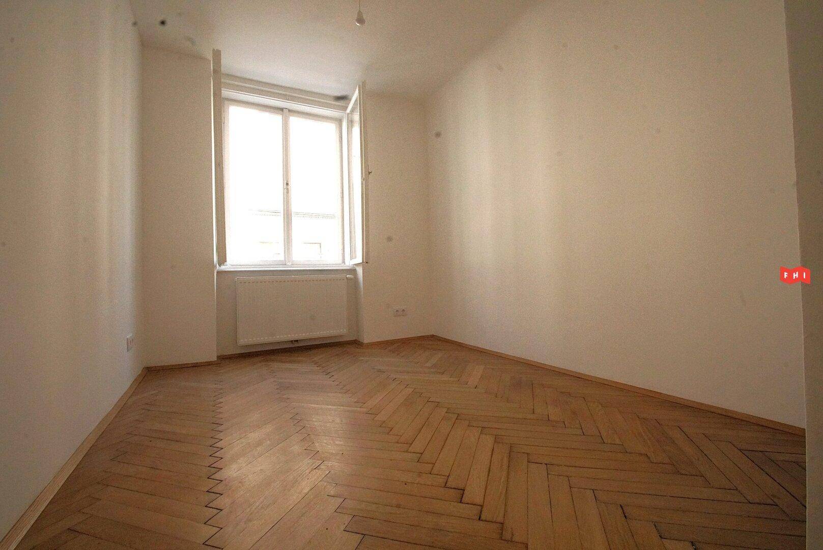 Ein schlichter Raum mit Fischgrätparkett und einem Fenster, das sich zum Lüften öffnen lässt.