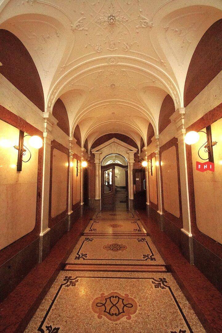 Ein prunkvoller Flur mit Gewölbedecke, Stuckverzierungen und gemustertem Terrazzoboden.