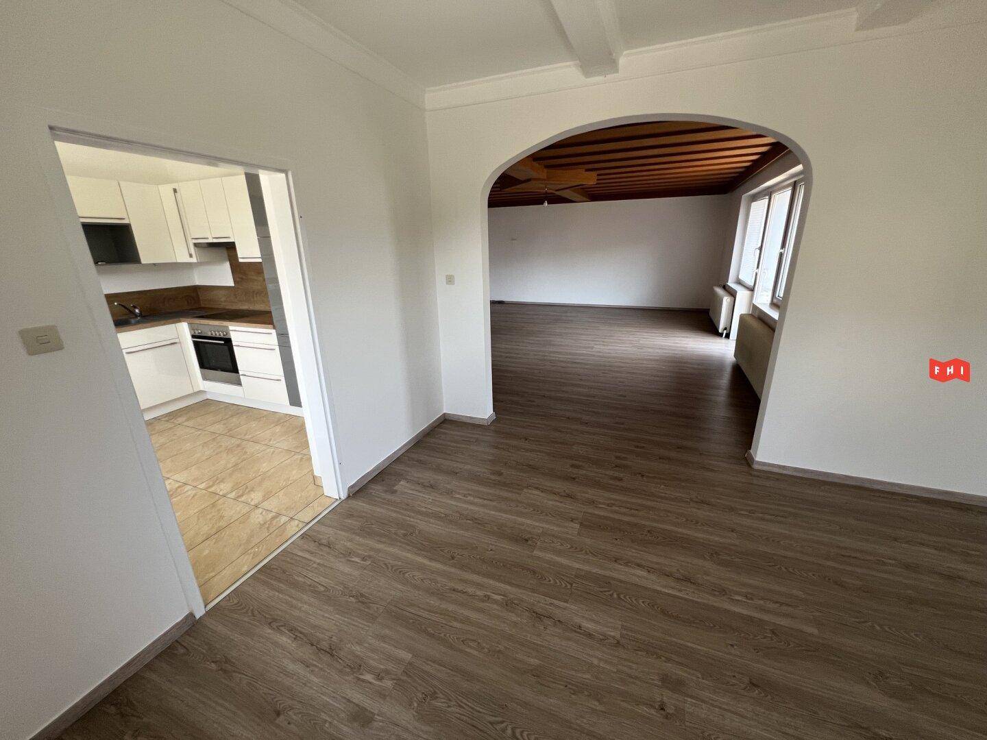 Offener Wohnbereich mit Laminatboden, Durchgang zur Küche und Blick in den hinteren Wohnraum.