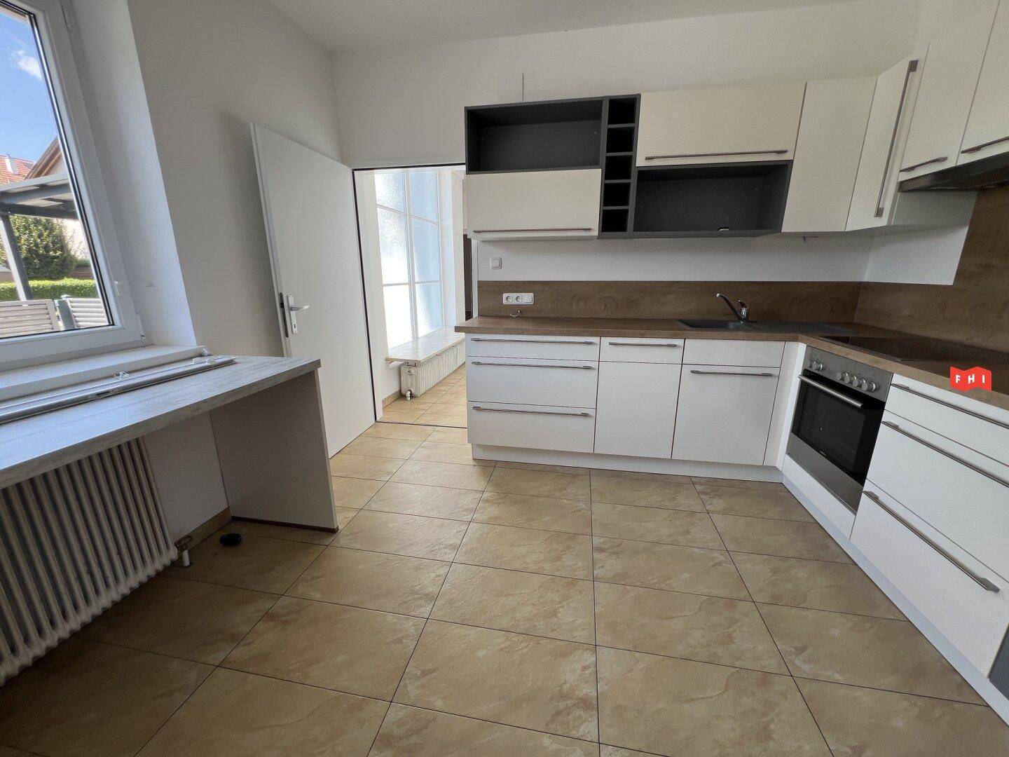 Moderne Küche mit weißen Schränken, Holzoptik-Arbeitsplatte und Fliesenboden.
