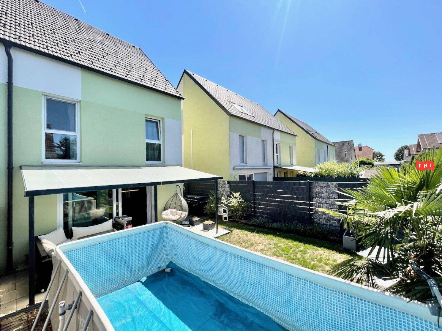 Sonniger Gartenbereich mit aufgestelltem Pool und Blick auf die benachbarten Reihenhäuser.