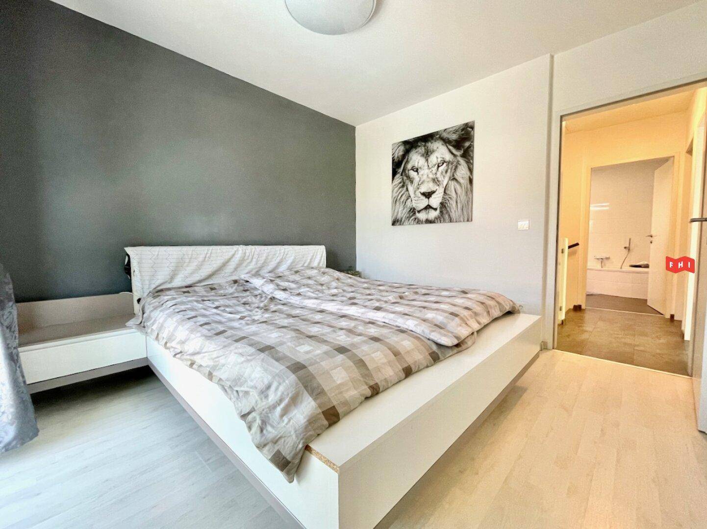 Schlafzimmer mit Doppelbett, Akzentwand und direktem Zugang zum Badezimmer.
