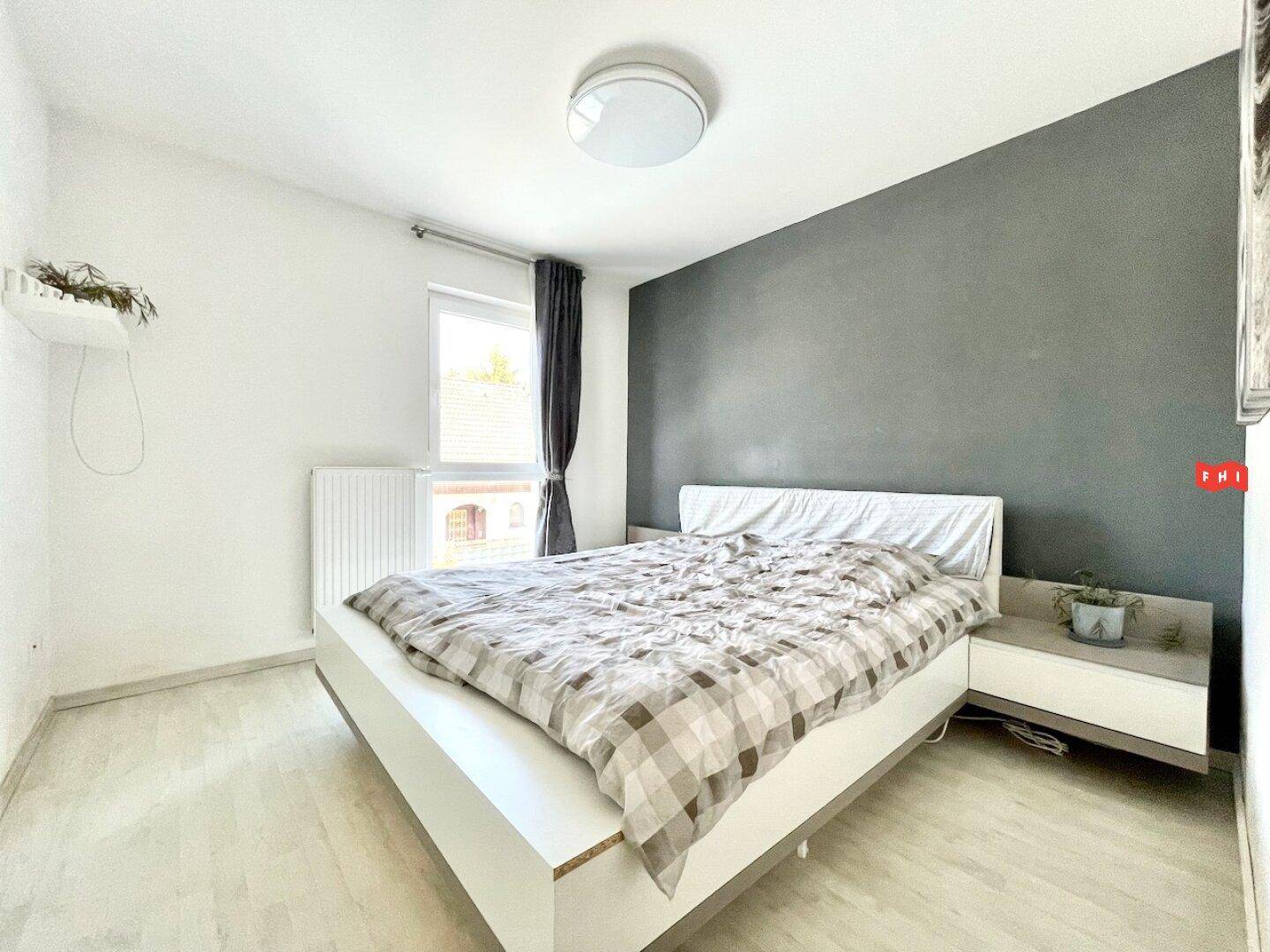 Helles Schlafzimmer mit großem Bett, Fenster und schlichter, moderner Einrichtung.
