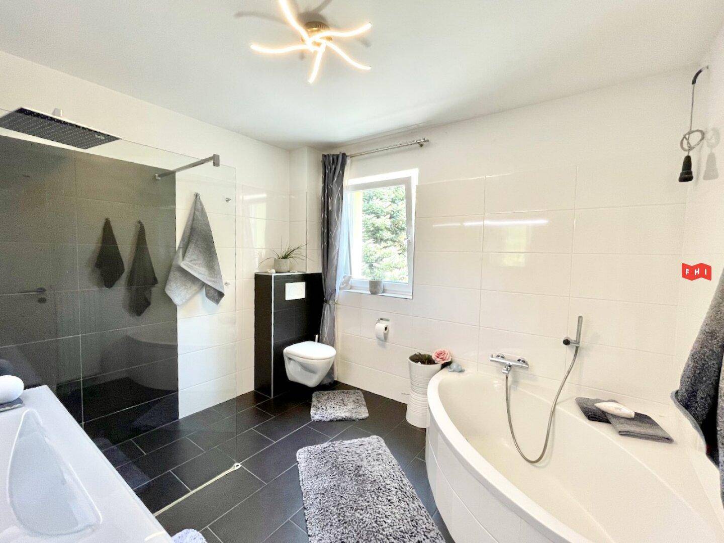 Modernes Badezimmer mit großer begehbarer Dusche, Badewanne und Fenster.
