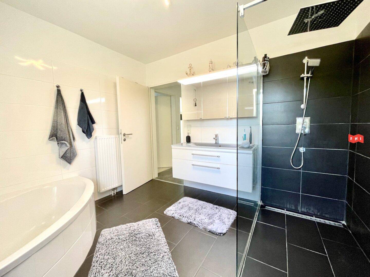 Geräumiges Badezimmer mit Doppelwaschbecken, großer Dusche und Eckbadewanne.