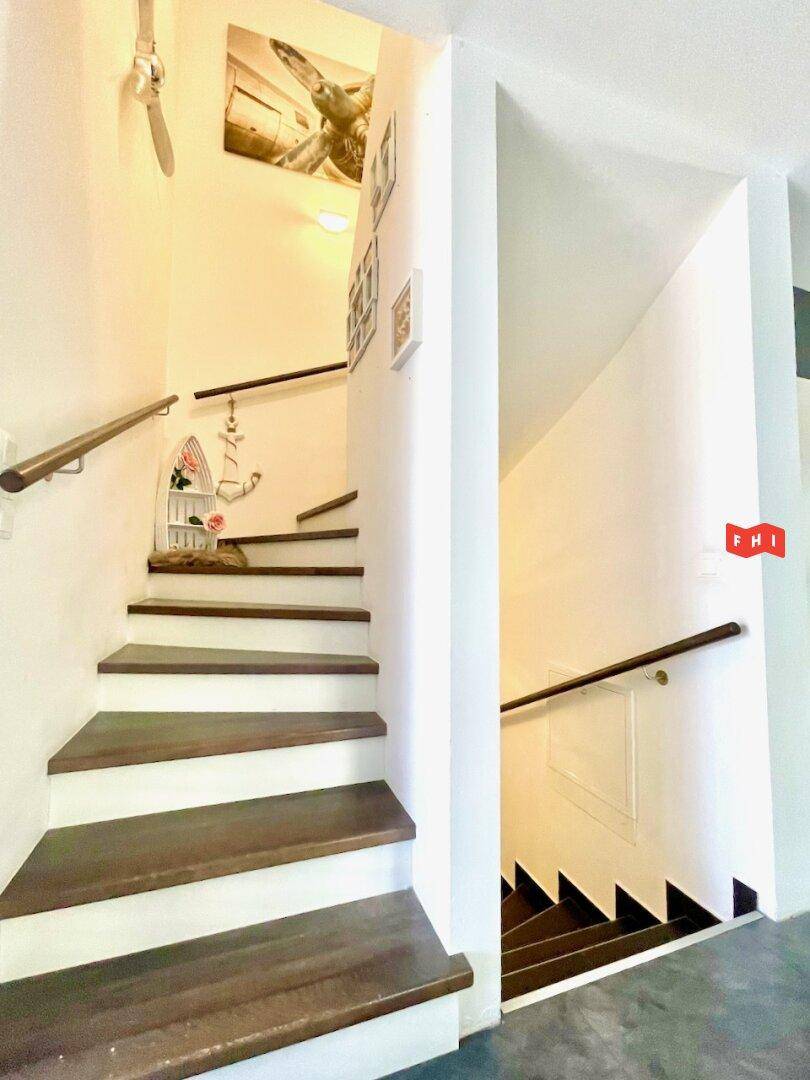 Treppenhaus mit Holzstufen und Handlauf, das die verschiedenen Ebenen des Hauses verbindet.