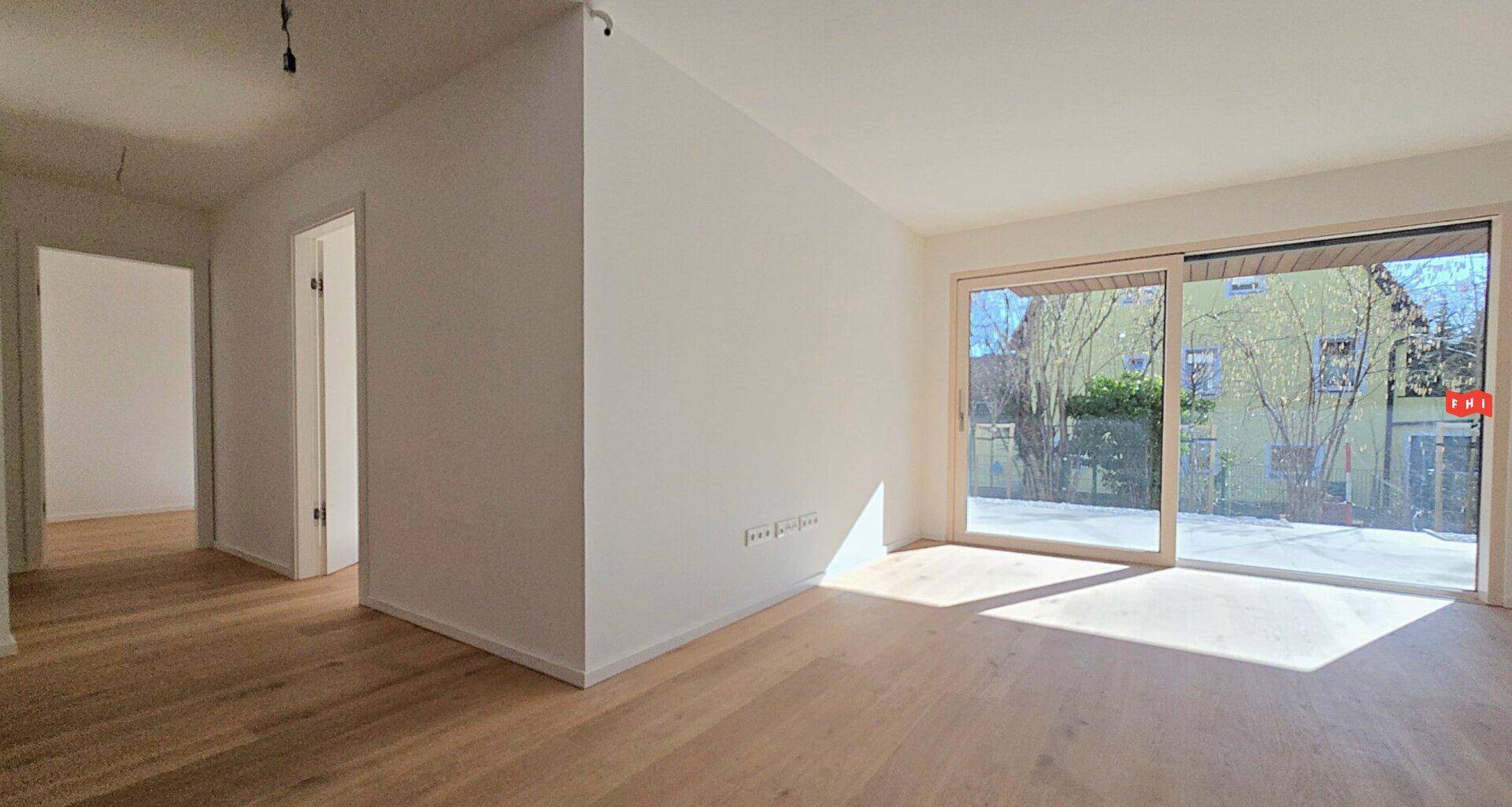 Lichtdurchfluteter Raum mit Holzboden und Zugang zu einem Außenbereich.