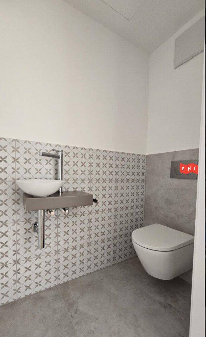 Modernes Gäste-WC mit stilvollen Fliesen, Wand-WC und kleinem Waschbecken.