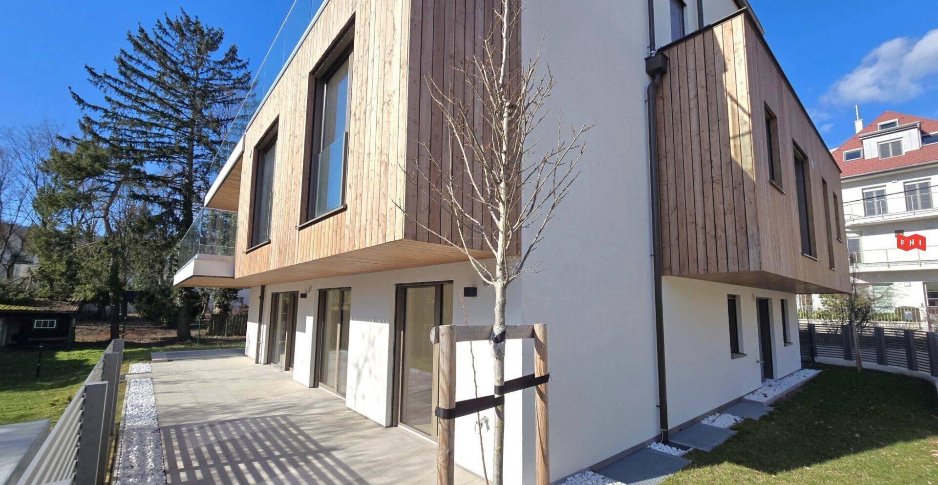 Moderne Architektur mit Holzverkleidung und weißer Fassade in grüner Umgebung.