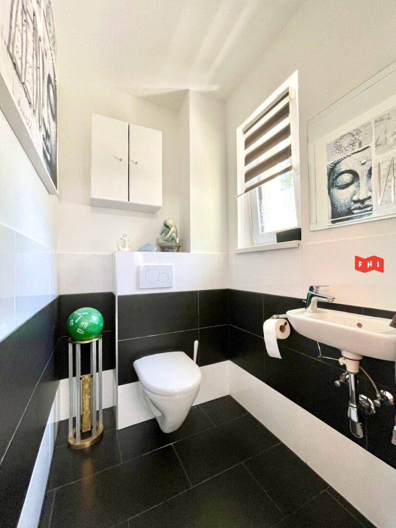 Gäste-WC mit Wand-WC, kleinem Waschbecken und kontrastreichen Schwarz-Weiß-Fliesen.
