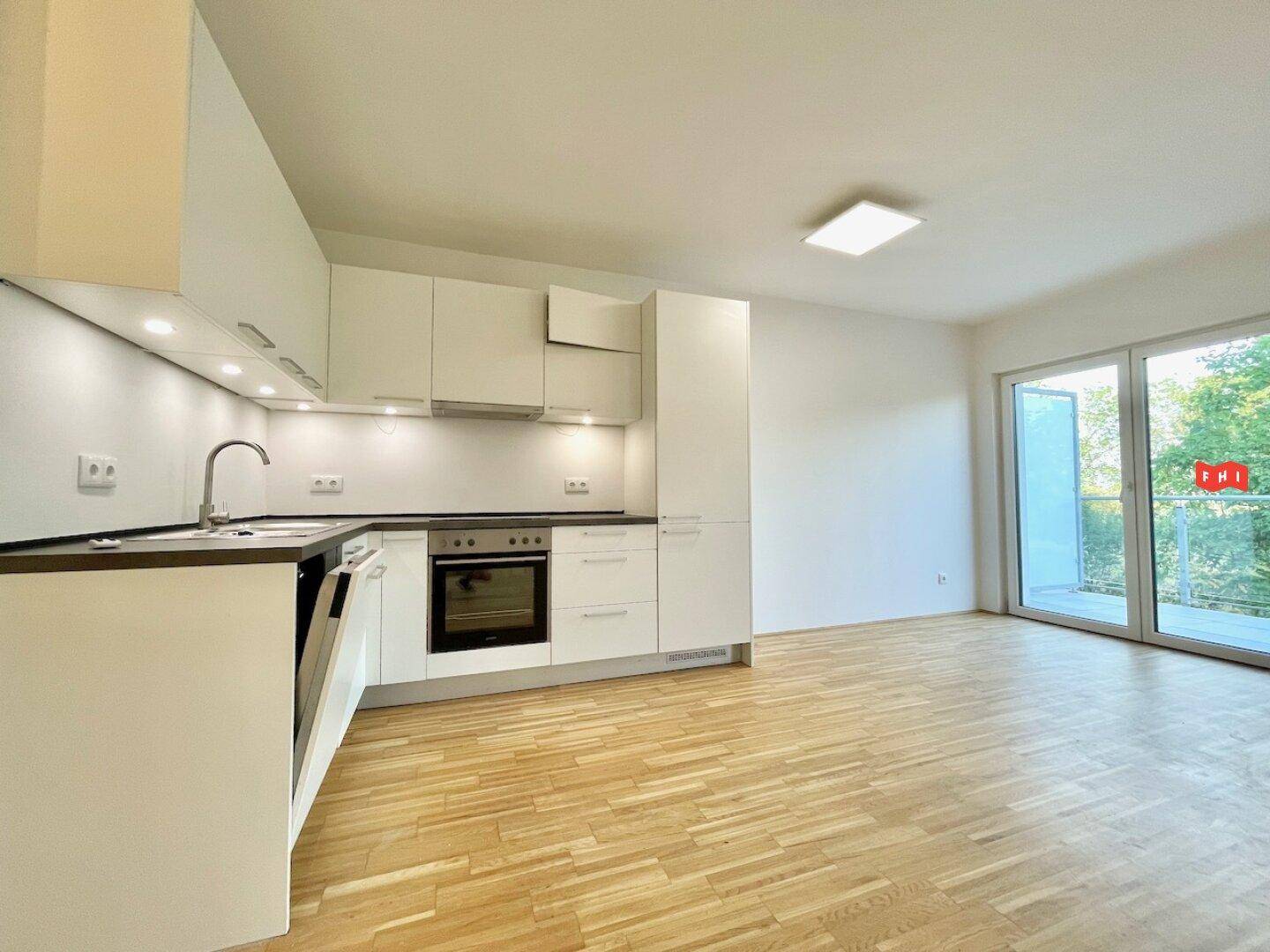 Helle Einbauküche mit weißen Fronten und direktem Zugang zum Balkon.