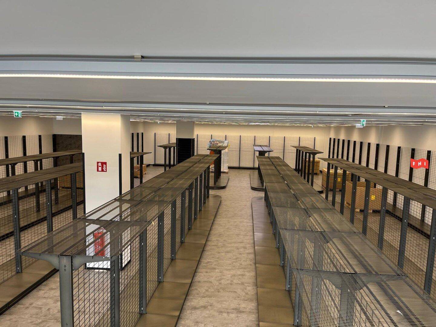 Geräumiger, unmöblierter Verkaufsraum mit modernen Regalsystemen und heller Deckenbeleuchtung, bereit zur Nutzung.