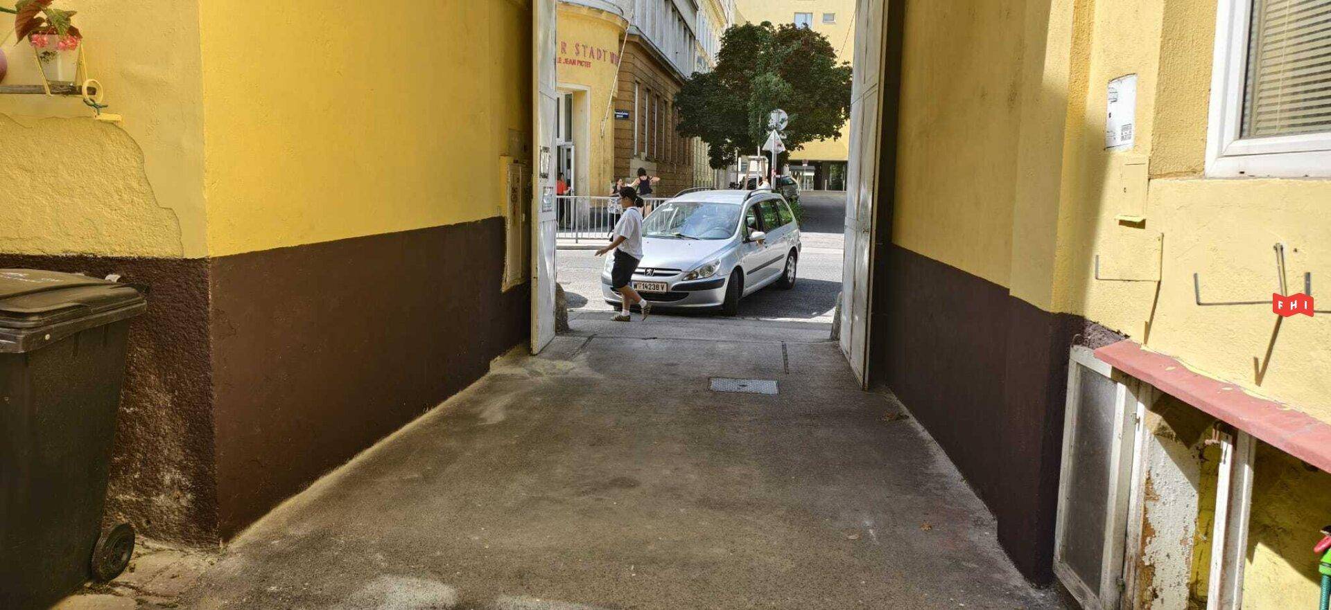 Durchgang von einem Gebäude zur Straße mit Blick auf den Stadtverkehr und umliegende Häuser.
