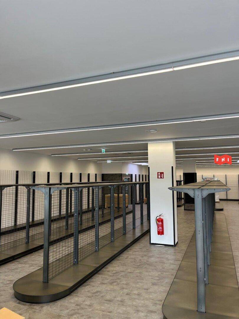 Leerer Verkaufsraum mit Regalsystemen und moderner Beleuchtung, bereit für die Bestückung mit Waren.